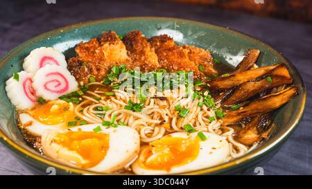 Knuspriges Hühnchen-katsu-Ramen mit weichgekochtem Ei, Bambussprossen und naruto-Fischkuchen. Reichhaltige, herzhafte Brühe. Perfektes japanisches Komfortessen in einer Schüssel. Stockfoto