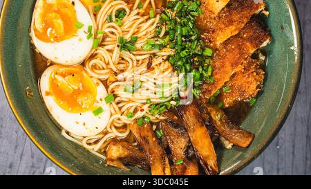 Knuspriges Hühnchen-katsu-Ramen mit weichgekochtem Ei, Bambussprossen und naruto-Fischkuchen. Reichhaltige, herzhafte Brühe. Perfektes japanisches Komfortessen in einer Schüssel. Stockfoto