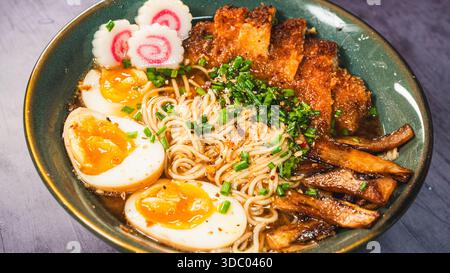 Knuspriges Hühnchen-katsu-Ramen mit weichgekochtem Ei, Bambussprossen und naruto-Fischkuchen. Reichhaltige, herzhafte Brühe. Perfektes japanisches Komfortessen in einer Schüssel. Stockfoto