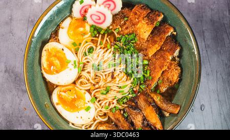 Knuspriges Hühnchen-katsu-Ramen mit weichgekochtem Ei, Bambussprossen und naruto-Fischkuchen. Reichhaltige, herzhafte Brühe. Perfektes japanisches Komfortessen in einer Schüssel. Stockfoto