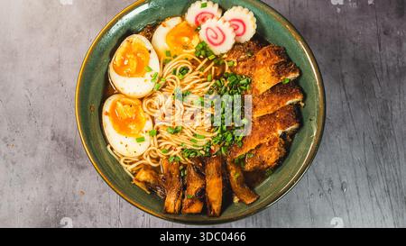 Knuspriges Hühnchen-katsu-Ramen mit weichgekochtem Ei, Bambussprossen und naruto-Fischkuchen. Reichhaltige, herzhafte Brühe. Perfektes japanisches Komfortessen in einer Schüssel. Stockfoto