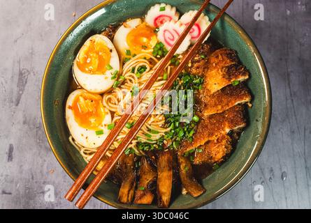 Knuspriges Hühnchen-katsu-Ramen mit weichgekochtem Ei, Bambussprossen und naruto-Fischkuchen. Reichhaltige, herzhafte Brühe. Perfektes japanisches Komfortessen in einer Schüssel. Stockfoto