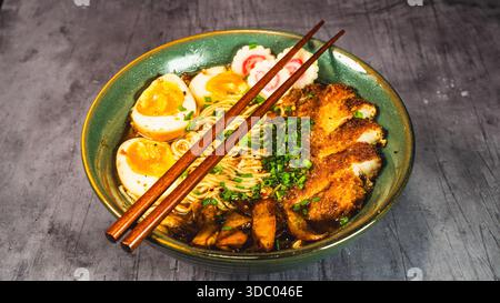 Knuspriges Hühnchen-katsu-Ramen mit weichgekochtem Ei, Bambussprossen und naruto-Fischkuchen. Reichhaltige, herzhafte Brühe. Perfektes japanisches Komfortessen in einer Schüssel. Stockfoto