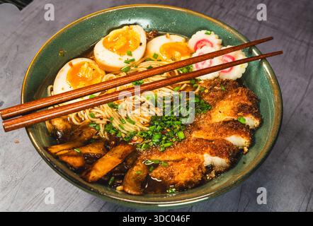 Knuspriges Hühnchen-katsu-Ramen mit weichgekochtem Ei, Bambussprossen und naruto-Fischkuchen. Reichhaltige, herzhafte Brühe. Perfektes japanisches Komfortessen in einer Schüssel. Stockfoto