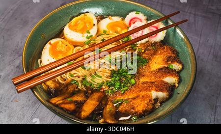 Knuspriges Hühnchen-katsu-Ramen mit weichgekochtem Ei, Bambussprossen und naruto-Fischkuchen. Reichhaltige, herzhafte Brühe. Perfektes japanisches Komfortessen in einer Schüssel. Stockfoto