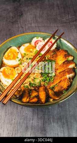 Knuspriges Hühnchen-katsu-Ramen mit weichgekochtem Ei, Bambussprossen und naruto-Fischkuchen. Reichhaltige, herzhafte Brühe. Perfektes japanisches Komfortessen in einer Schüssel. Stockfoto