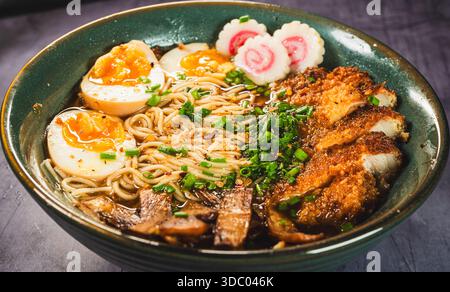 Knuspriges Hühnchen-katsu-Ramen mit weichgekochtem Ei, Bambussprossen und naruto-Fischkuchen. Reichhaltige, herzhafte Brühe. Perfektes japanisches Komfortessen in einer Schüssel. Stockfoto