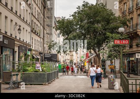 PARIS, FRANKREICH - 22. JUNI 2025: Blick auf die Rue du Temple im Marais, Paris, mit Fußgängern, Geschäften und klassischen Fassaden mit einem alten Metro-Schild Stockfoto