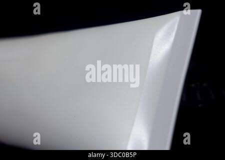 Selektive Fokusnaht des gecrimpten Endes einer leeren weißen Druckröhre vor dunklem Hintergrund, was auf Kosmetikcreme, Zahnpasta oder medizinische Zwecke hindeutet Stockfoto