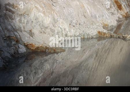 Unterirdische Höhle mit klarem Salzwasser, das raue graue Mineralsteinmauern reflektiert, die kalte Atmosphäre in tiefer Höhlenlandschaft zeigen Stockfoto