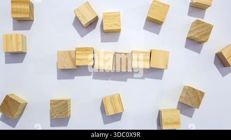 Holzblöcke, die Linie mit verstreuten Würfeln auf weißem Hintergrund bilden Stockfoto