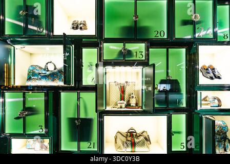 Luxuriöse Handtaschen und Schuhe im beleuchteten grünen Boutique-Fenster mit nummerierten Fächern Stockfoto