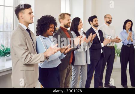 Junge Geschäftsleute stehen in einer Reihe beim Treffen im Büro und klatschen die Hände. Stockfoto