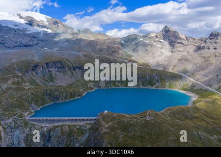 Aus der Vogelperspektive des Lago Goillet Wasserkraftwerks oberhalb der Valtournenche in den italienischen Alpen, umgeben von felsigen Gipfeln und Spätsommerschneefeldern. Stockfoto