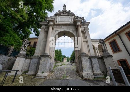 Flacher Blick auf den Arco del Rosario auf dem Pilgerweg Sacro Monte di Varese, barockes Tor aus Stein, das zu Kapellen am Hügel führt. Stockfoto