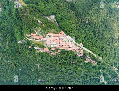Vertikale Luftlinie einer mit Terrakotta überdachten Bergsiedlung, umgeben von dichten Wäldern in den Voralpen bei Varese. Stockfoto