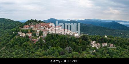 Aus der Vogelperspektive auf ein Dorf auf einem Hügel in der Nähe von Varese, mit Terrakottadächern und dichten Wäldern vor den Voralpen. Stockfoto