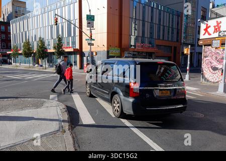 Zwei Fußgänger überqueren eine Straße mit einem Autofahrer in einem Kleinbus mit dem Kennzeichen GBR 2292 des Bundesstaats New York und hielten mitten auf einem Straßenübergang in New York Stockfoto