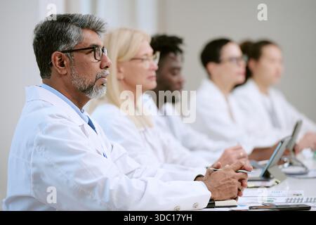 Diverse Gruppe von Ärzten mittleren Alters und jungen Erwachsenen, die an der Konferenz teilnehmen Stockfoto