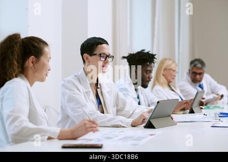 Multiethnische Gruppe von Wissenschaftlern mittleren Alters, die mit digitalen Tablets zusammenarbeiten Stockfoto