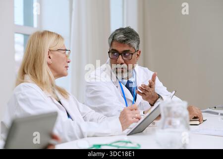 Frau mittleren Alters und südasiatischer Mann mittleren Alters diskutieren medizinischen Bericht Stockfoto