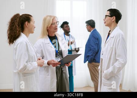Gruppe verschiedener medizinischer Fachkräfte, die die Patientenversorgung im Krankenhaus diskutieren Stockfoto
