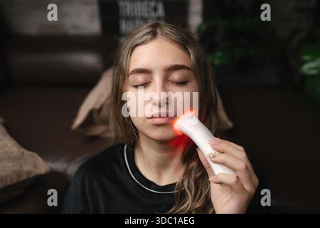 Nahaufnahme einer jungen Frau mit Lichttherapie-Gadget zu Hause Stockfoto
