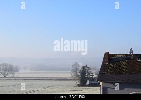 Neuschnee auf den Feldern mit Nebel darüber Stockfoto