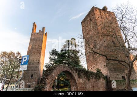 Rovigo, italien 18. dezember 2025: Mittelalterliche Backsteintürme und der alte Bogen von rovigo, italien, getaucht in warmes, goldenes Licht bei Sonnenuntergang über dem historischen venetien Stockfoto