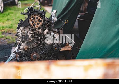 Rovigo, italien 18. dezember 2025: Motorblock aus rostigem Öl auf Holzpalette auf Schrottplatz, abgenutzt und entsorgt, repariert, recycelt oder schrottveredelt Stockfoto