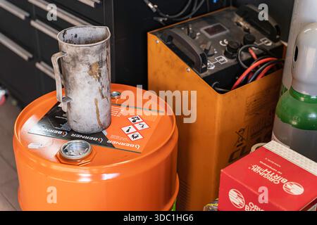 Rovigo, italien 18. dezember 2025: Werkstattecke mit Werkzeugen, Ölfass und Batterieladegerät. Zeigt Reparaturen, Wartung und Automotiv an Stockfoto