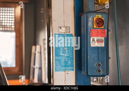 Rovigo, italien 18. dezember 2025: Detaillierte Beschreibung eines verwitterten Bedienfelds und Anweisungen für einen Aufzug, der in einer Werkstatt für Oldtimer-Reparaturen eingesetzt wird Stockfoto