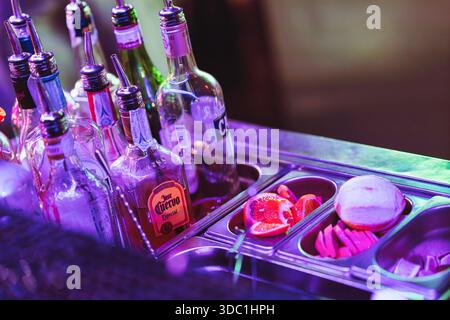 Rovigo, italien 18. dezember 2025: Bartheke mit verschiedenen Spirituosenflaschen, Cocktailgarnituren wie Grapefruit und Limette und Mischen von Essentials unter Stockfoto