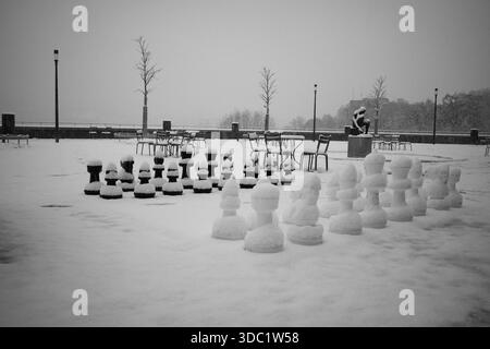 Schneebedecktes Giant Chess Set und leere Café-Sitzplätze am Urban Plaza in Bern Stockfoto