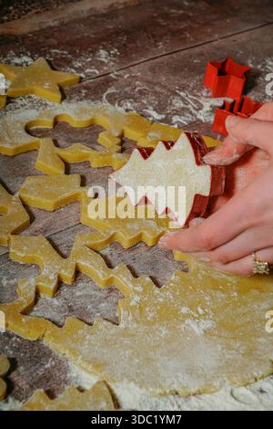 Eine junge Frau, die Weihnachtskekse ausschneidet Stockfoto