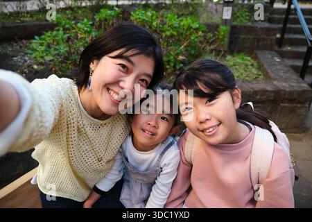 Japanische Mutter und Töchter machen glückliches Selfie draußen Stockfoto