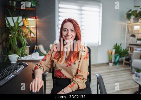 Junge Geschäftsfrau lächelt und arbeitet vom Home Office aus Stockfoto