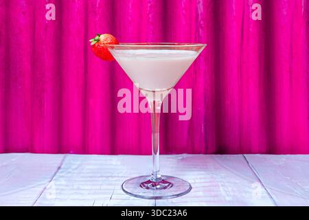 Ein Cocktailglas mit einem Getränk auf Erdbeerbasis auf einem hellen Tisch Stockfoto