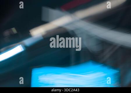 Abstrakte, chaotische Nachtlichter in der Stadt verschwimmen. Diagonale weiße und zyanblaue Bewegungsstreifen auf dunklem Hintergrund, die die Energie der Stadt darstellen. Stockfoto