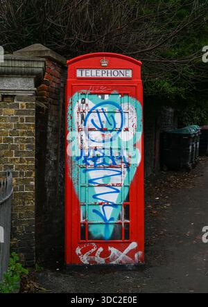 Alte öffentliche Telefonbox mit Graffiti bedeckt am Eingang zum St. Nicholas Rest Garden in Brighton Sussex, UK 2025 Stockfoto