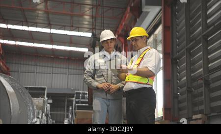Industriearbeiter, der in einem großen Metallrohr in einer Fabrik einen Schutzhelm trägt || Modell veröffentlicht Stockfoto