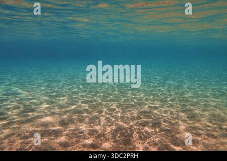 Unterwasserblick, sandiger Meeresboden und transparentes Wasser. Lebenspendendes Sonnenlicht unter Wasser. Stockfoto