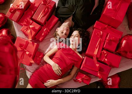 Junger Mann und junge Frau liegen umgeben von Valentinsgeschenken Stockfoto