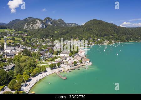 Blick aus der Vogelperspektive auf den ruhigen türkisfarbenen See, der auf die malerische Stadt Saint Gilgen trifft, eingebettet vor der Kulisse der grünen Berge Saint Gilgen, Salz Stockfoto