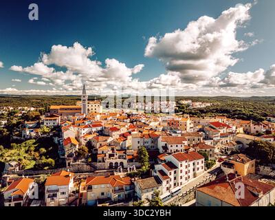Blick aus der Vogelperspektive auf die Terrakotta-Dächer, die hinunterragen, um auf das schimmernde Adria-Meer zu treffen, mit dem Glockenturm durch die Skyline, Vrsar, County Istrien, Stockfoto