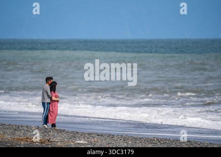 Liebevolles Paar vor den Wellen des pazifiks am Shizuoka Beach Stockfoto