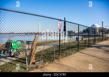 WASHINGTON DC USA // WASHINGTON, D.C. — Eine umzäunte Bauzone für das Tidal Basin Seawall Reconstruction Project steht entlang der Uferpromenade, mit dem Jefferson Memorial und dem Washington Monument im Hintergrund, Donnerstag, 18. Dezember 2025. Dieses Projekt befasst sich mit jahrzehntelanger Bodensenkung und steigendem Meeresspiegel, die tägliche Gezeitenfluten entlang der ursprünglichen Küste des Beckens aus dem 19. Jahrhundert verursachen. Die Salzwasserflut beschädigt die Wurzelsysteme der berühmten Yoshino-Kirschbäume (*Prunus x yedoensis*), ein Geschenk von J 1912 Stockfoto