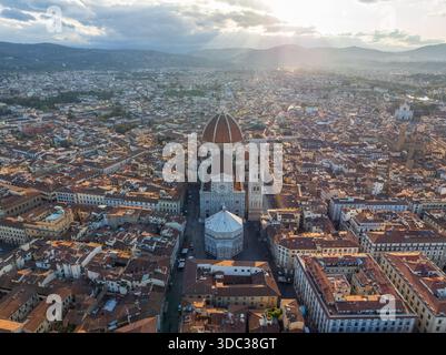 Aus der Vogelperspektive auf die Terrakotta-Kuppel des Duomo und Giottos Campanile durchdringen die Skyline inmitten eines Meeres aus rustikalen Dächern, die in das goldene Licht von Tu getaucht sind Stockfoto