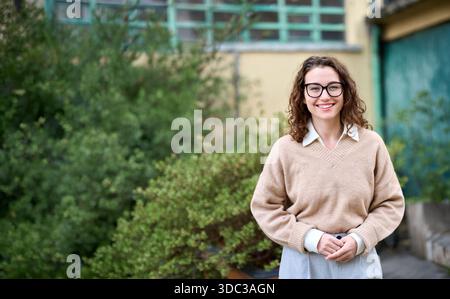 Junge lächelnde professionelle Geschäftsfrau im Freien stehend, vertikales Porträt. Stockfoto