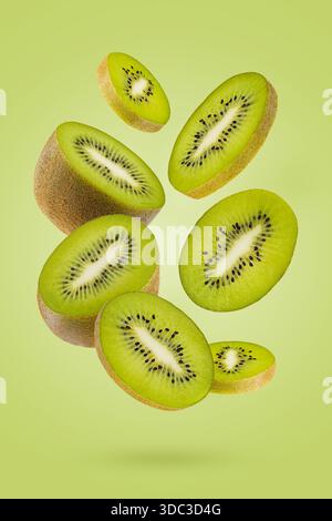 Kiwi-Früchte mit sattem grünem Fruchtfleisch, schwarze Samen fliegen als Fluss auf grünem Hintergrund. Perfekt für Werbung für organische Antioxidantien, Entgiftungsmenü, fi Stockfoto